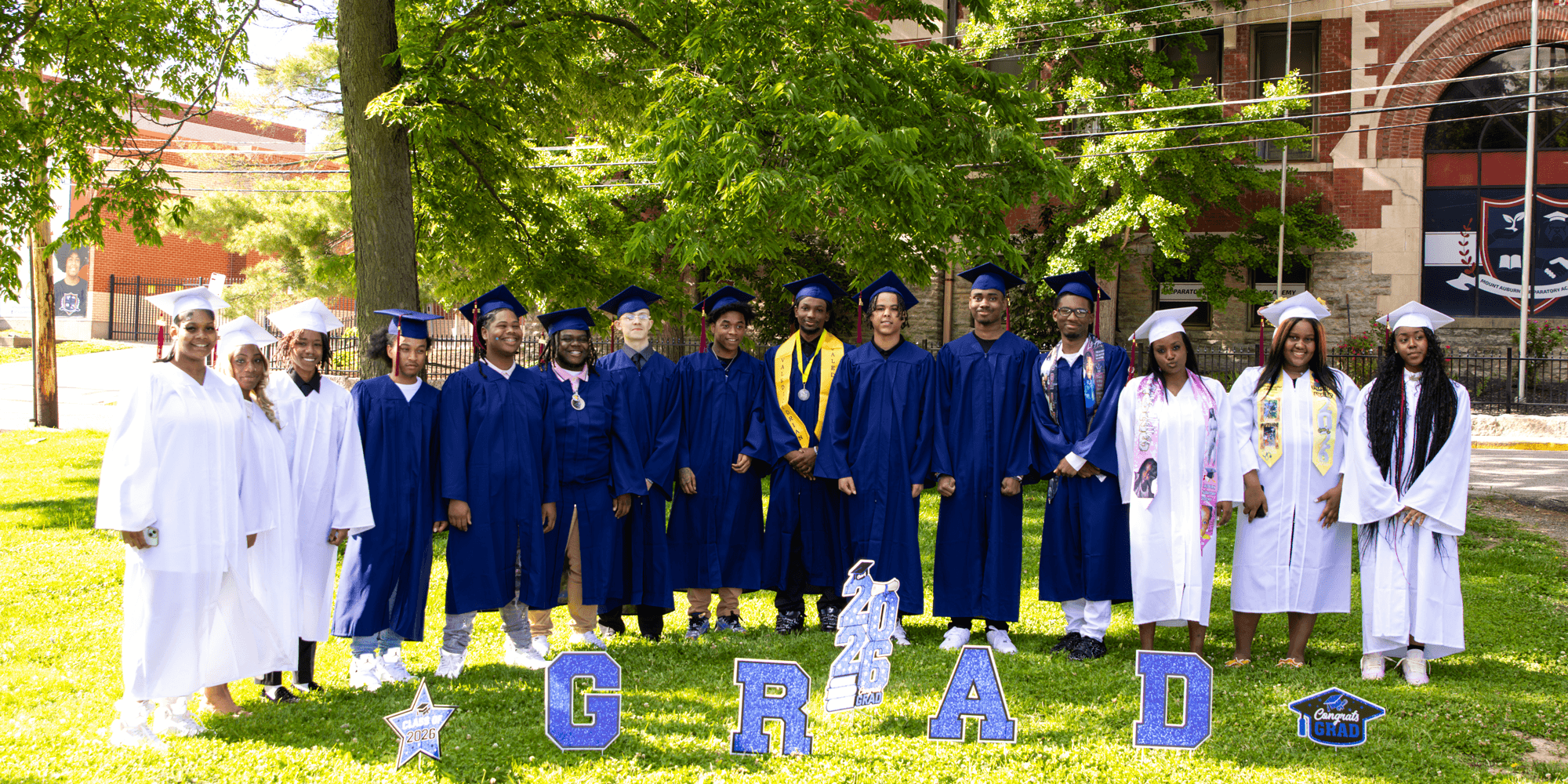 Graduates in caps and gowns pose with "GRAD" letters.