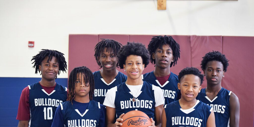 Group of basketball players at the gymnasium with one holding a basketball