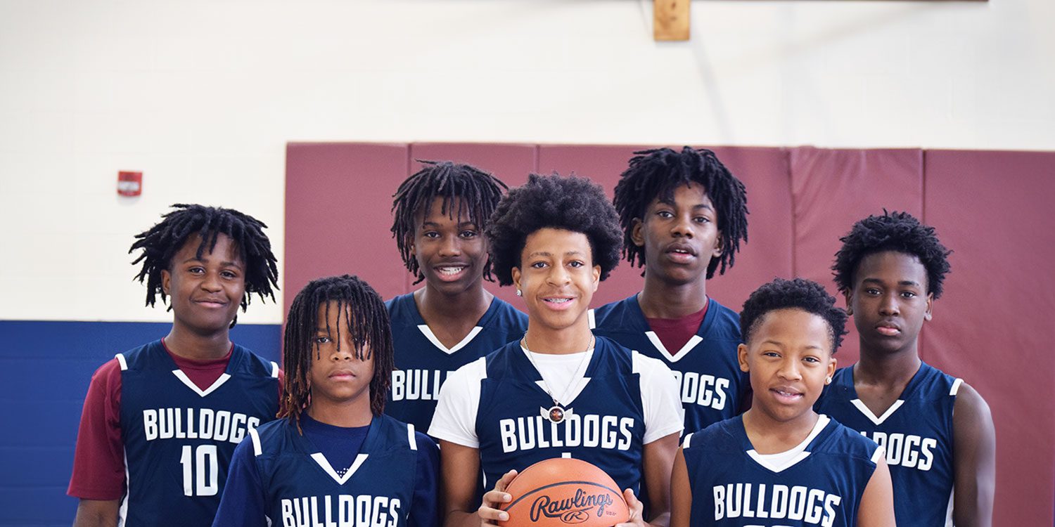 Group of basketball players at the gymnasium with one holding a basketball