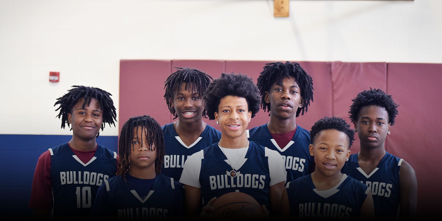 Group of basketball players at the gymnasium with one holding a basketball